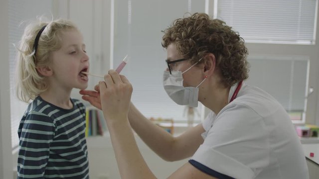 Doctor In Mask Using Swab To Test For Coronavirus On Little Boy