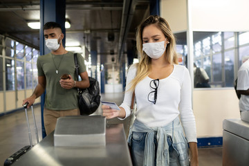 Coronavirus disease. Woman uses the boarding pass to access the boarding area. Young worker wears...