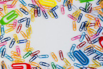 Colorful paperclips on the white surface, designed frame shape.Conceptual imagge of education with copy space