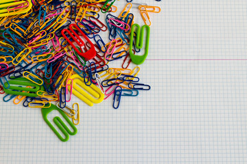 Obraz na płótnie Canvas Colorful paperclips heap on the white,checkered paper surface with copy space.Conceptual image of education.