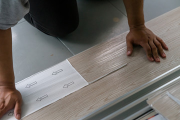Fototapeta na wymiar A person installing new vinyl tile floor, a DIY home project.