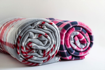 Rolled two different color and size fleece blankets on the white background,close taken.
