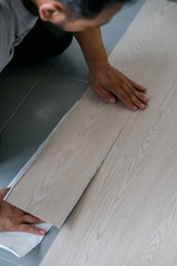 Fototapeta na wymiar A person installing new vinyl tile floor, a DIY home project.
