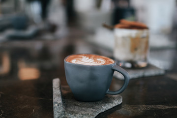 Fresh brewed coffee beautiful cup of cappuccino with latte art in the wooden space background. Trendy toning. Minimal composition, hipster vibes. Top view, flat lay copy space for your text.