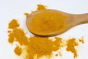 Turmeric powder in a wooden spoon isolated on a white background is an ingredient in turmeric foods and ingredients in skin care products. Turmeric helps the skin to be strong.