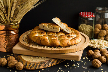Ramadan breads on wooden tray with wheat ears,walnuts and grains on black surface.