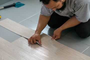 Kuala Lumpur, Malaysia - March 1, 2020: A man installing new vinyl tile floor, a DIY home project.