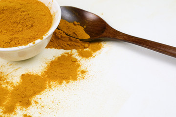 Turmeric powder in a wooden spoon and isolated white cup on a white background Used as an ingredient in skin care and food products. Turmeric helps the skin to be strong.