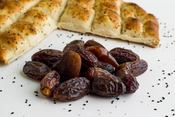 Fresh Ramadan bread,pide and star shape dry,date fruits on the white surface with sesame and nigella seeds.