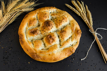 Traditional Turkish Ramadan Fresh Bread on black surface with wheat ears.
