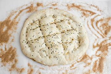 Prepared Traditional Turkish bread (pide) of Ramadan on the white surface with brown flour.Shaped it and ready for cook.Homemade.