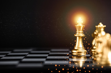 Gold color chess pieces on chessboard, focused on King piece. Business strategy concept. Business...