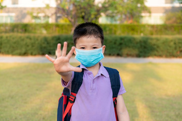 Covid-19 Coronavirus epidemic virus symptoms and Air pollution pm2.5 concept. Little Asian boy wearing mask for protect pm2.5 and show stop hands gesture for stop corona virus outbreak.