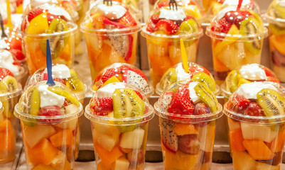 Rows of closed plastic cups with fruit salad on the counter