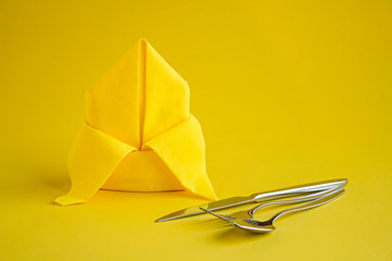 Luxury,Yellow Color Paper Napkin folded in bishop's hat or lily flower on the yellow background with cutlery set and copy space.Conceptual image for any holiday.