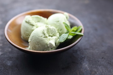 Scoop of green tea, pistachio ice cream. Dessert in a bowl on a dark background, close up