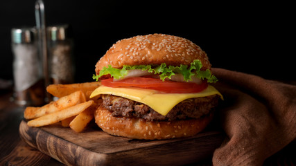 Close up view of Fresh tasty beef burger and french fries on wooden tray