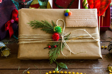 A present wrapped with kraft paper, green leaves and an empty label on the wooden table