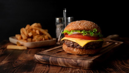 Close up view of Fresh tasty burger on wooden tray and french fries