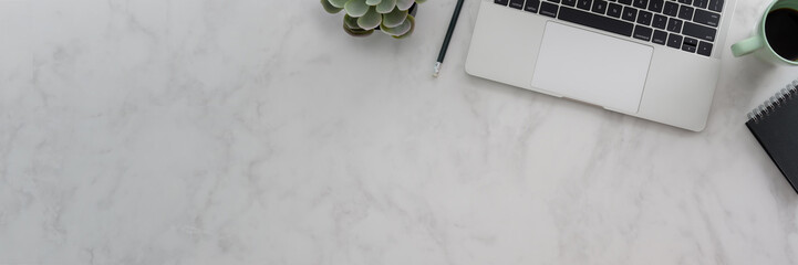 Overhead shot of workspace with laptop, stationery and copy space on marble desk