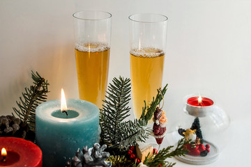 Blue large size candle in snowy pine leaves with two champagne glasses.Conceptual image of Merry Christmas or New Year 