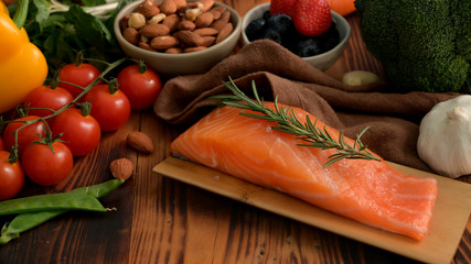 Cropped shot of ingredients for healthy food with salmon, fruits, vegetable and seeds on rustic table