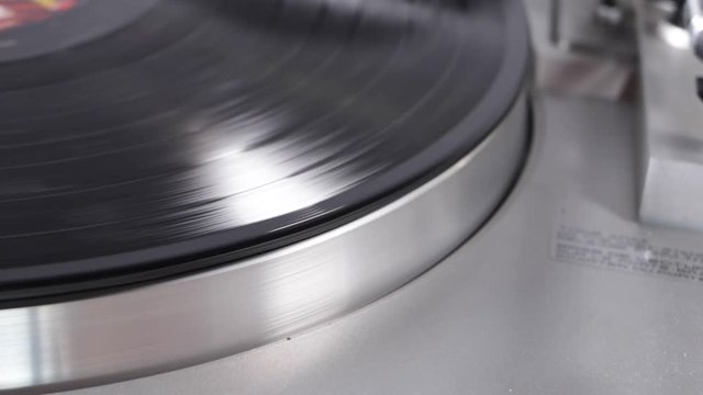 Close up of turntable needle on a vinyl record. Turntable playing vinyl. Needle on rotating black vinyl.