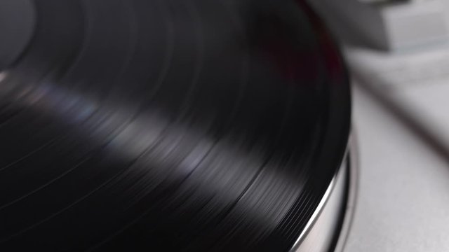 Close up of turntable needle on a vinyl record. Turntable playing vinyl. Needle on rotating black vinyl.