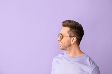 Young man with stylish sunglasses on color background