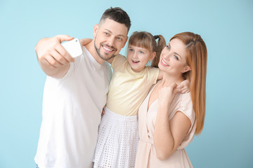 Family taking selfie on color background