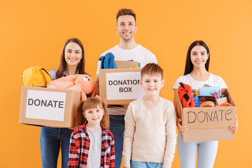 Volunteers with donations for orphans on color background