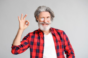 Stylish elderly man showing OK gesture on grey background