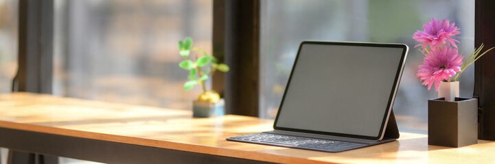 Cropped shot of portable workspace with blank screen tablet on wooden counter bar