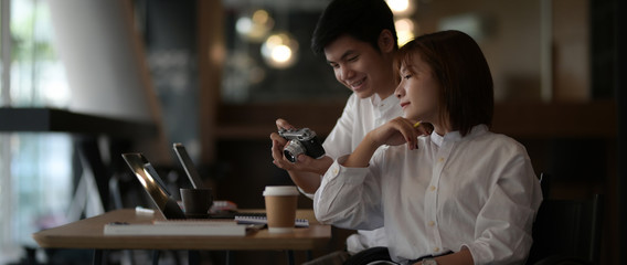 Cropped shot of two photographer consulting on their work with camera and laptop
