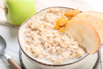 Bowl with tasty sweet oatmeal on table, closeup