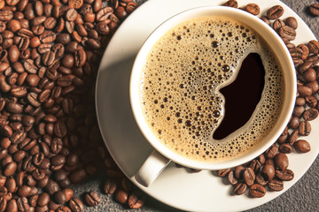 Cup of hot coffee and beans on table