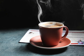 Cup of hot coffee and newspaper on table