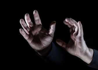 Hands show a gesture of defense against a black background