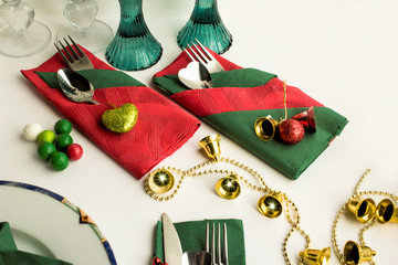 Christmas green and red colors paper napkins folded in various shapes on white surface with cutlery set and christmas decoration