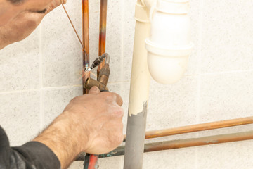 Pipework. Plumbing contractor works sweating the joints on the copper pipe domestic water system