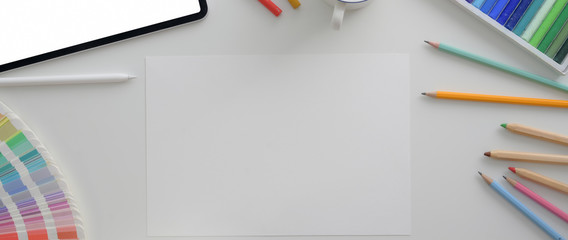 Overhead shot of designer workplace with mock-up tablet, sketch paper and designer supplies