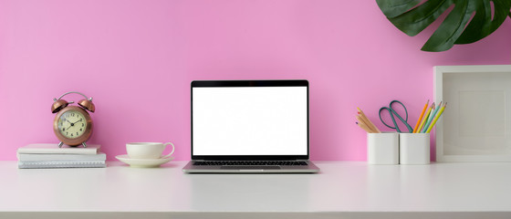 Close up view of feminine workspace with blank screen laptop, supplies and decorations