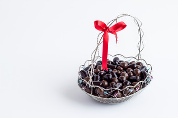 Dark Ball Shape Chocolates in stylish metal basket with red color ribbon on white with copy space.