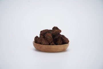 The dried plum is in a wooden bowl. It's on a white background