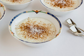 Traditional Turkish Rice Pudding in stylish bowls on white with spoon
