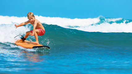 Happy baby boy - young surfer learn to ride on surfboard with fun on sea waves. Active family...