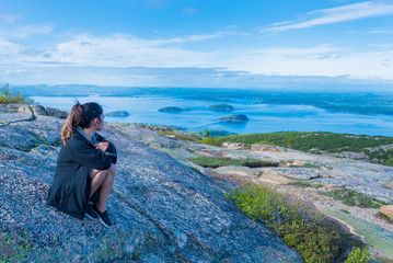 Woman enjoying the beautiful view of small islands seen from Cadillac mountain in Acadia National Park Maine USA