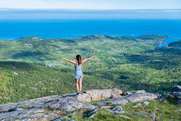 Woman enjoying the beautiful view of small islands seen from Cadillac mountain in Acadia National Park Maine USA