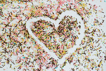 Colorful Sprinkles Sugar Strands, Vermicelli cake, cupcake decorations background with drawn heart shape.