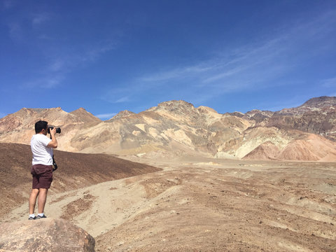 Man taking photograph of Artists palette at Death Valley National Park in California USA